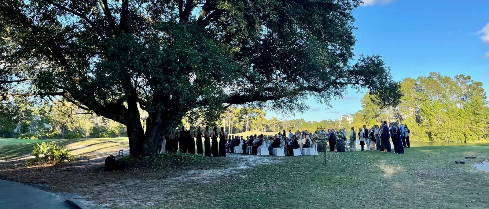 Outdoor ceremony gathering under the oak tree at St. James Bay